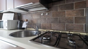 A modern kitchen with a stainless steel sink, a gas stove, and a microwave.