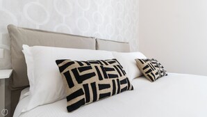 A bed with white bedding and two decorative pillows with a geometric pattern. - Italianway - Dei Transiti 7 (Milan)