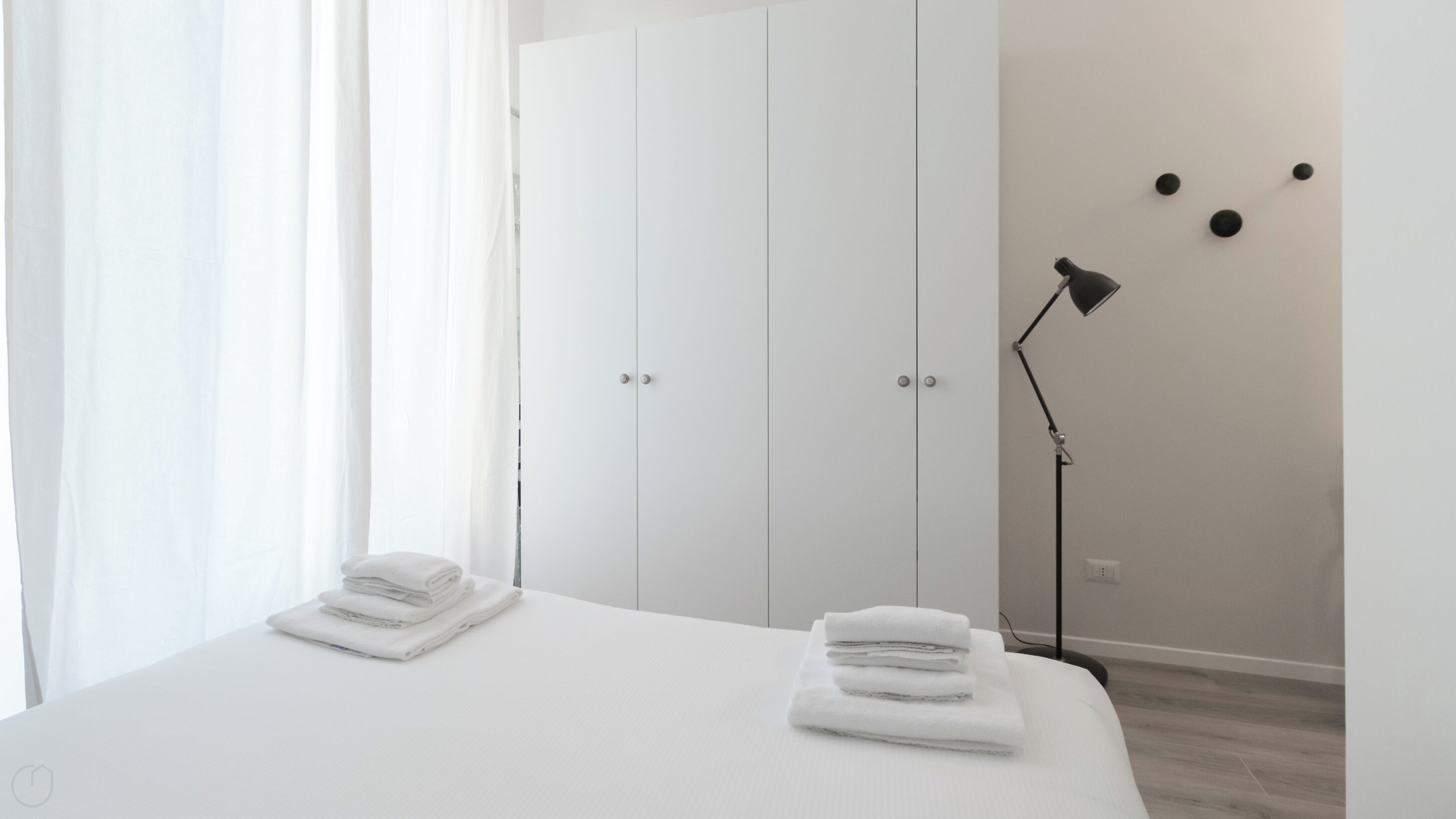 Een hotelkamer met een bed, een kledingkast en een vloerlamp.