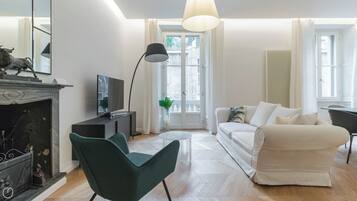 Ett modernt vardagsrum med en öppen spis, en tv, en soffa och en matplats.