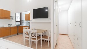 Eine moderne Küche mit Holzausstattung, einem weißen Esstisch und einem flachbildfernseher an der Wand.