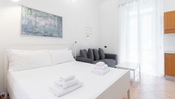 Ein modernes Schlafzimmer mit einem großen Bett, einem grauen Sofa und einem Bild an der Wand.