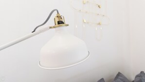 Eine weiße Schreibtischlampe mit flexiblem Schwanenhals und goldfarbenem Fuß, an der Decke montiert.