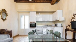 A modern kitchen with white cabinets, a glass dining table, and a wooden ceiling. - Italianway Easy - Ripa Ticinese 53 B (Milan)