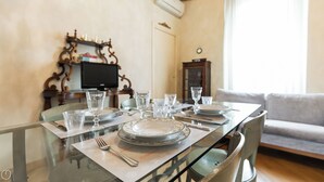 A dining table set with plates, glasses, and cutlery, with a television and decorative items in the background. - Italianway Easy - Ripa Ticinese 53 B (Milan)
