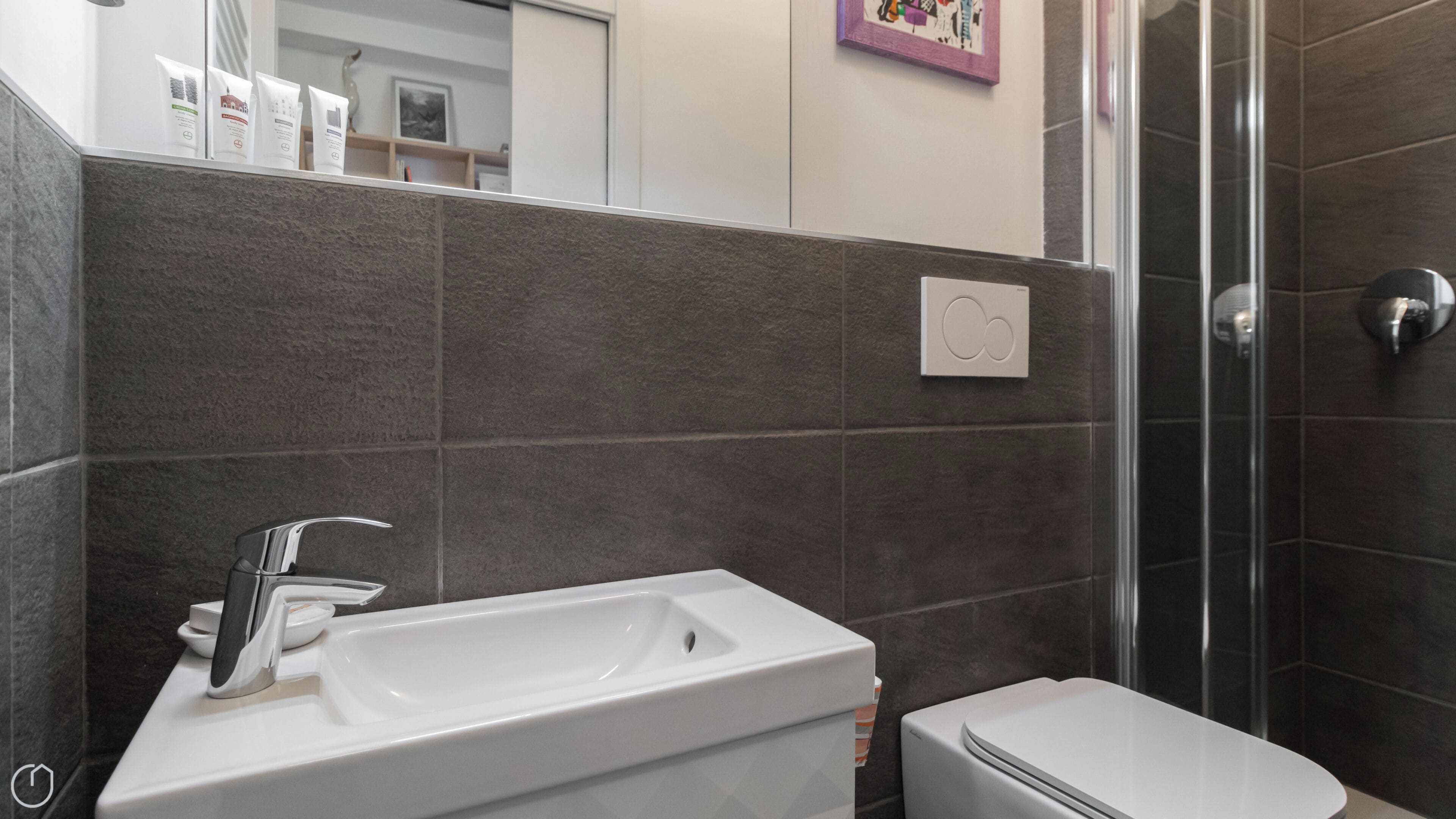 A bathroom with a white sink, a mirror, a shower area, and a toilet.
