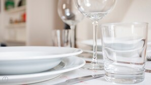 Et spisebord med en hvid tallerken, et glas og et glas vand.