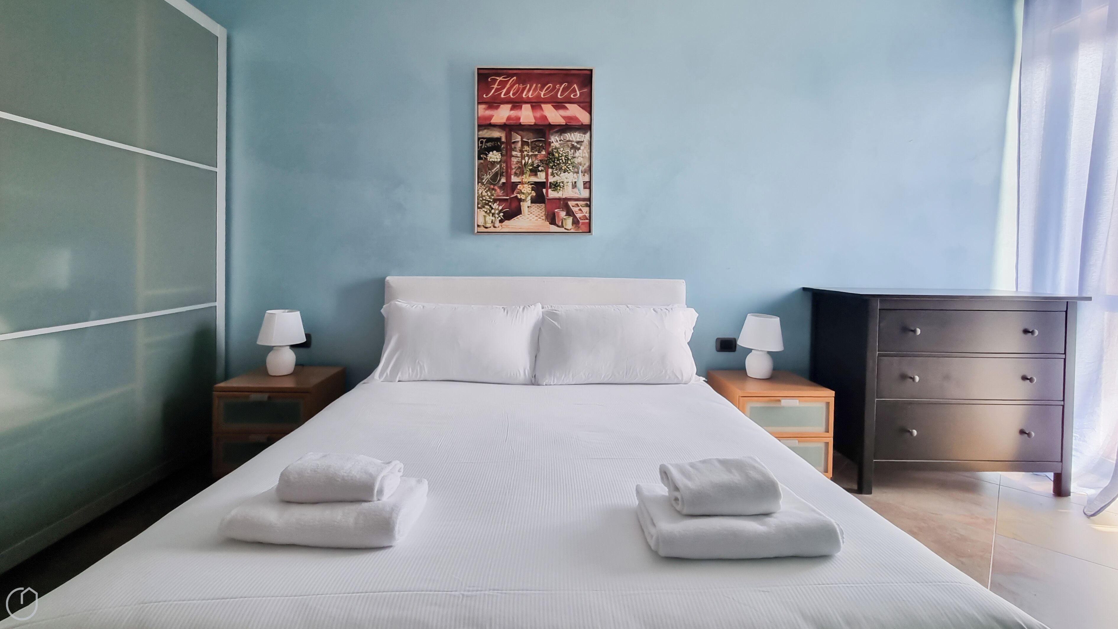 A hotel room with a large bed, two bedside tables with lamps, a dresser, and a framed picture on the wall.