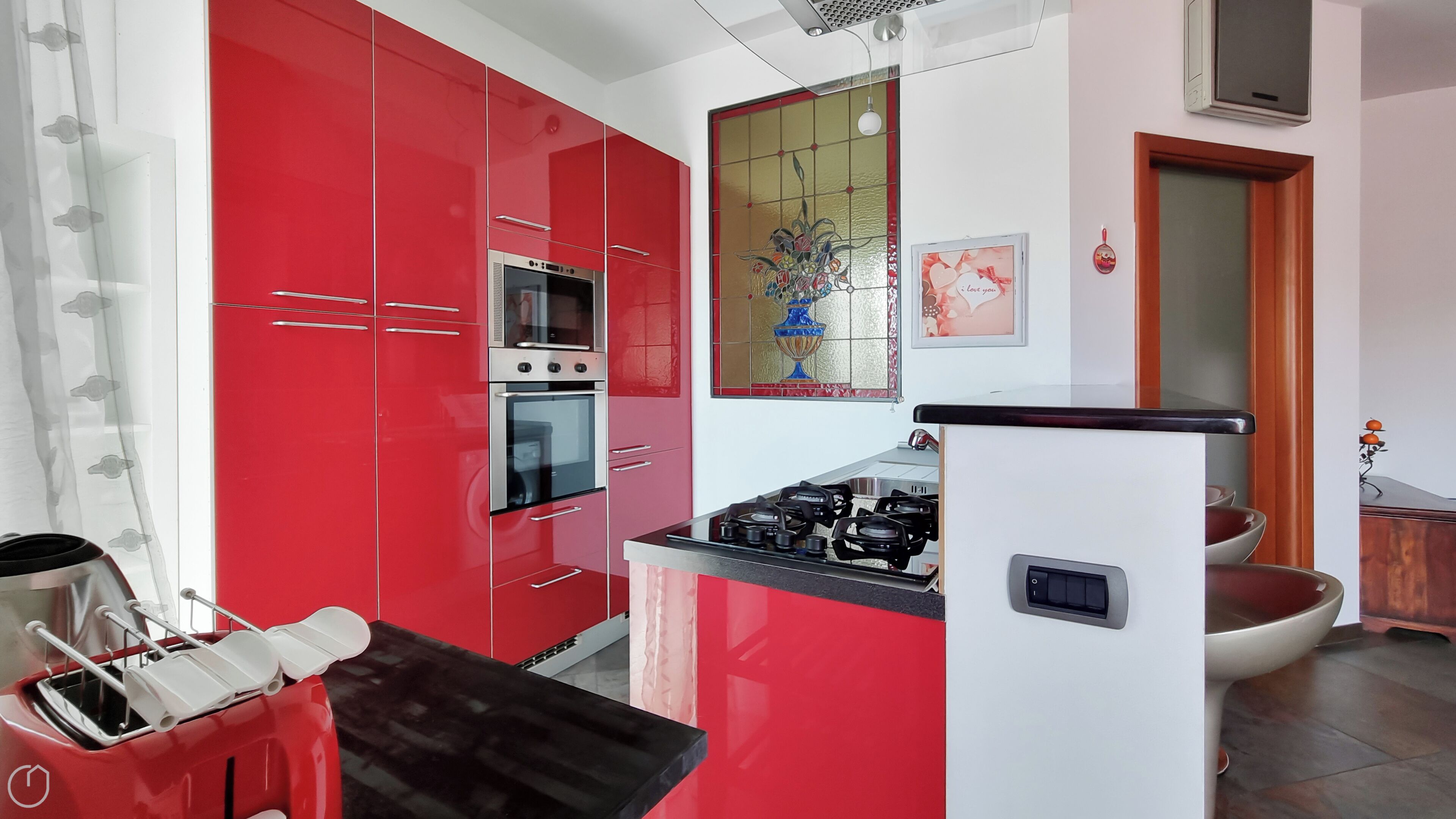 A kitchen with red cabinets, a gas stove, an oven, and a microwave.