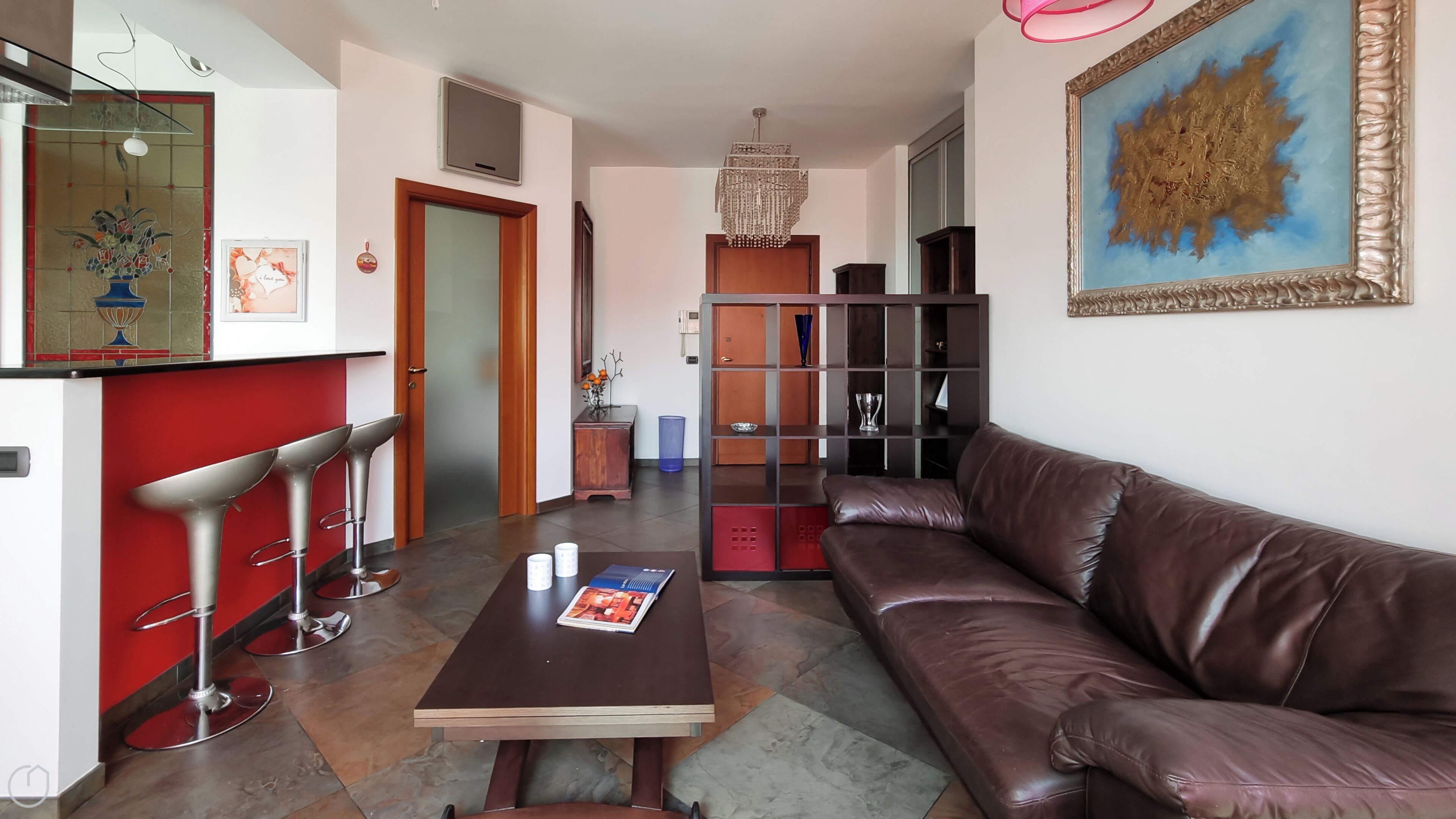 A living room with a brown leather sofa, a wooden coffee table, and a red accent wall.