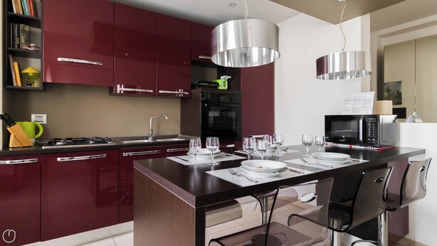 A modern kitchen with red cabinets, a central island with seating, a microwave, and a stove. - Italianway Easy - Dall'ongaro 24 (Milan)