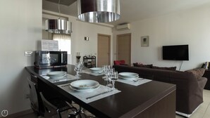 A modern kitchen with a central island, dining table set with plates and glasses, and a brown sofa in the background. - Italianway Easy - Dall'ongaro 24 (Milan)