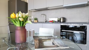 Una cucina moderna con un tavolo in vetro, un vaso con tulipani e una rivista.