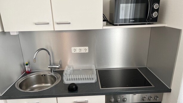 Een moderne keuken met roestvrijstalen apparatuur, een spoelbak en een magnetron.