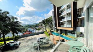 Varanda com vista para uma piscina, um carro estacionado e um edifício com várias unidades de ar condicionado.