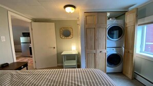 A bedroom with a bed, a washing machine, and a small table. - Top Floor River View Apartment (Kingfield)