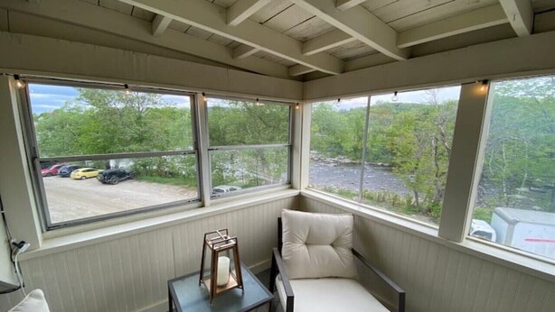 A cozy room with a view of a parking lot and a river, featuring a cushioned chair and a small table with a candle. - Top Floor River View Apartment (Kingfield)