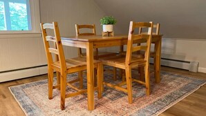 A dining table with four wooden chairs, a potted plant, and a patterned rug on a wooden floor. - Top Floor River View Apartment (Kingfield)