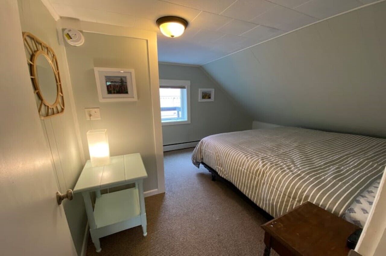 Un dormitorio con cama, escritorio, silla, mesita y ventana.