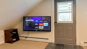 A flat-screen TV mounted on a wall, displaying a streaming service interface with various channel options. - Top Floor River View Apartment (Kingfield)