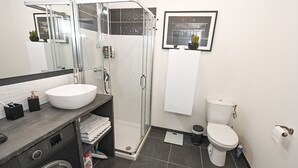A modern bathroom with a glass-enclosed shower, a white sink, and a toilet. - Magnifique Design T2, Confortable, Parking Gratuit (Nice)