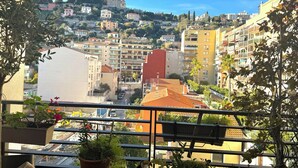 A balcony with potted plants and a view of a hillside with buildings. - Magnifique Design T2, Confortable, Parking Gratuit (Nice)