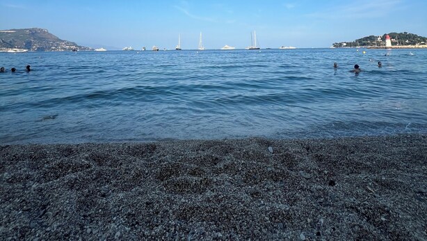 A coastal view with a pebbly beach, calm sea, and distant boats. - Magnifique Design T2, Confortable, Parking Gratuit (Nice)