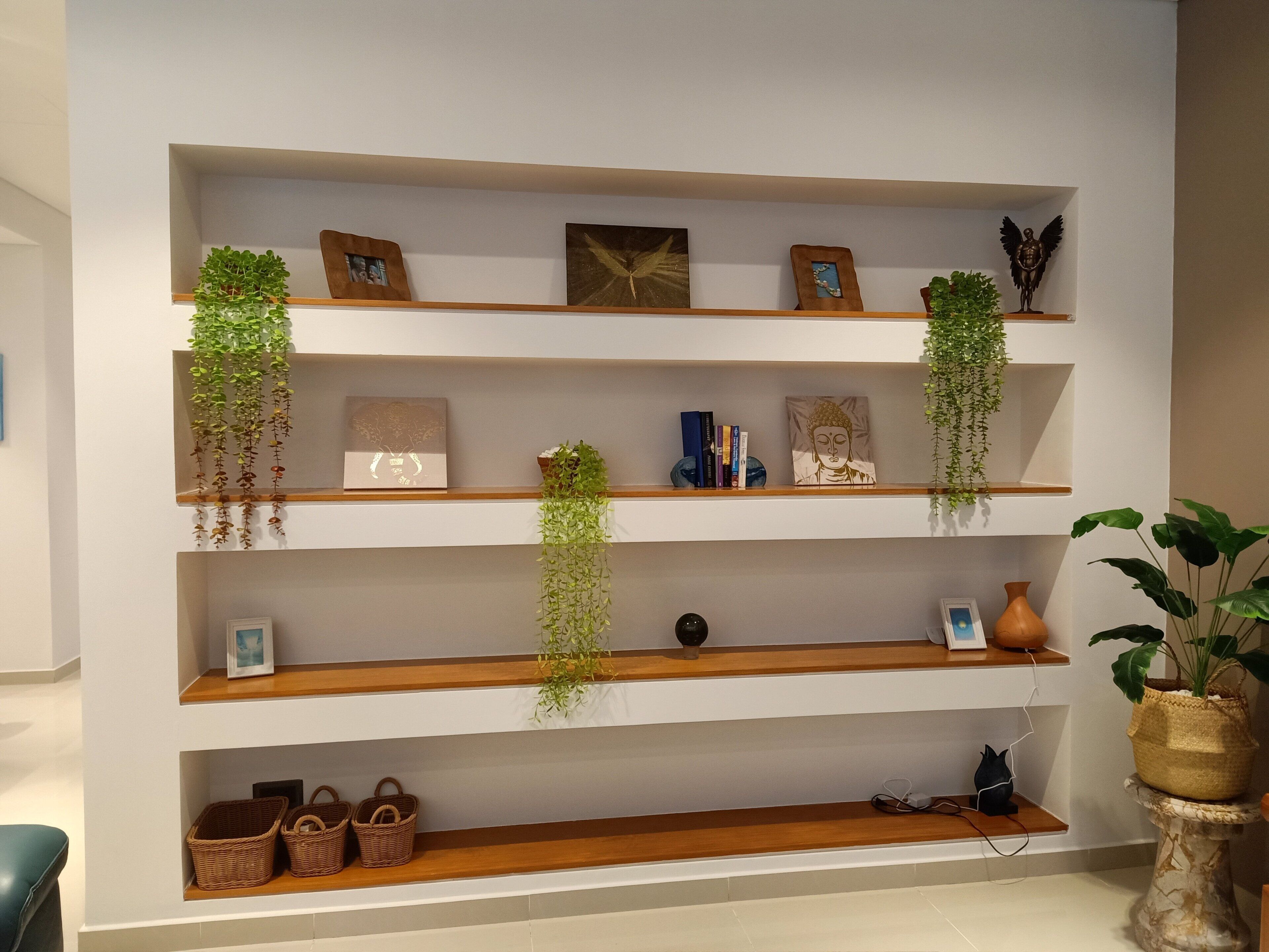 Eine Wand mit mehreren Holzregalen, die verschiedene Gegenstände wie gerahmte Bilder, Bücher und Dekorationsobjekte zeigen.