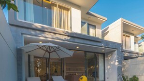 Een modern huis met een zwembad, terrasmeubels en een grote parasol.