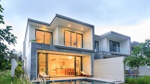 Een moderne twee verdiepingen tellende woning met een zwembad, grote glazen deuren en een verzorgde tuin.