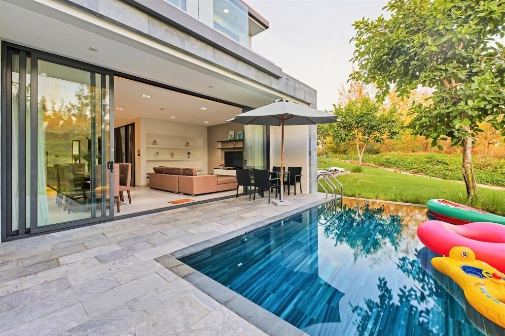 A modern house with a glass-enclosed patio and a swimming pool.