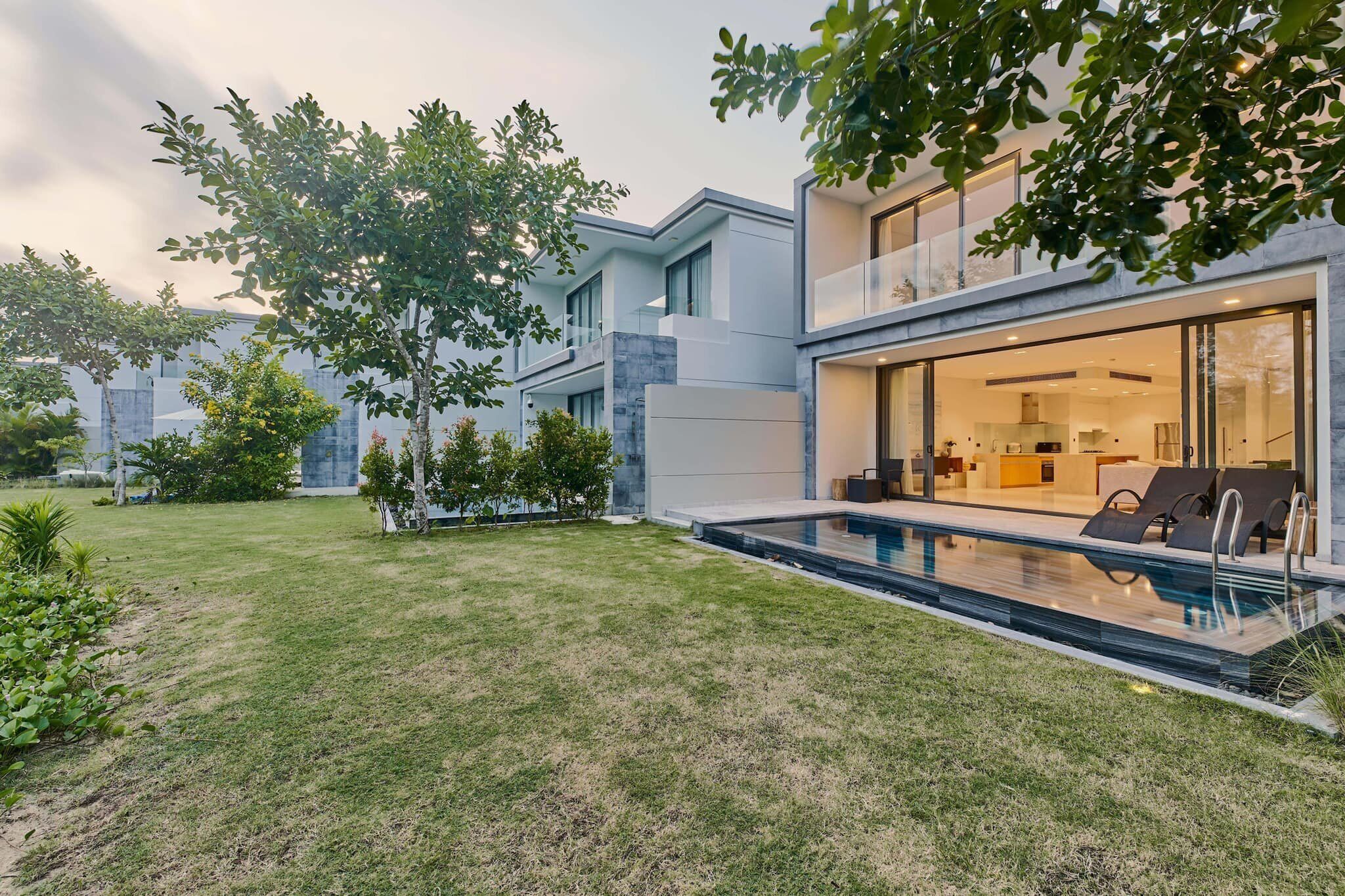 Une maison moderne dotée d’une piscine, d’un patio couvert et d’une pelouse bien entretenue.