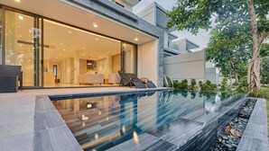 Een modern huis met zwembad, terras en een verzorgde tuin.