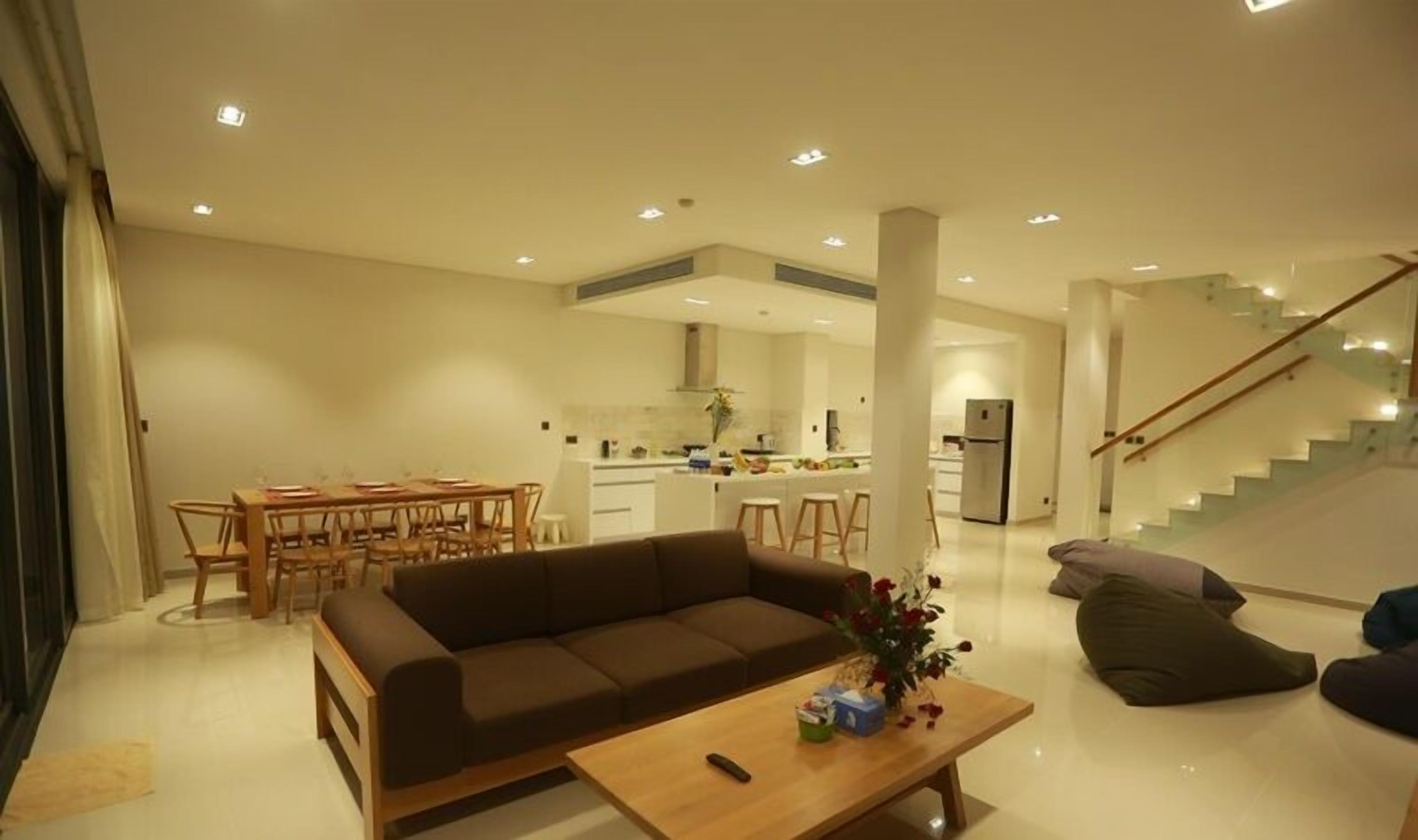 A modern living room with a sofa, coffee table, and a dining area with chairs and a table.