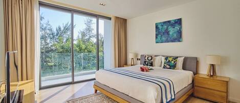 A modern bedroom with a large bed, a flat-screen TV, a wooden nightstand, and a view of trees through the window.