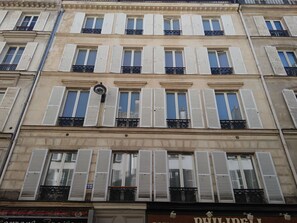 A multi-story building with white shutters on windows, balconies with black railings, and a sign with the name "PULVELL". - Multirésidence de l'Elysée (Paris)