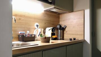 Une cuisine avec un plan de travail en bois, une bouilloire, une machine à café et un évier.