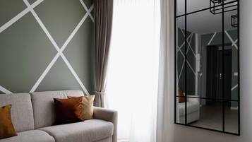 A modern living room with a sofa, a large mirror, and a geometric-patterned wall.