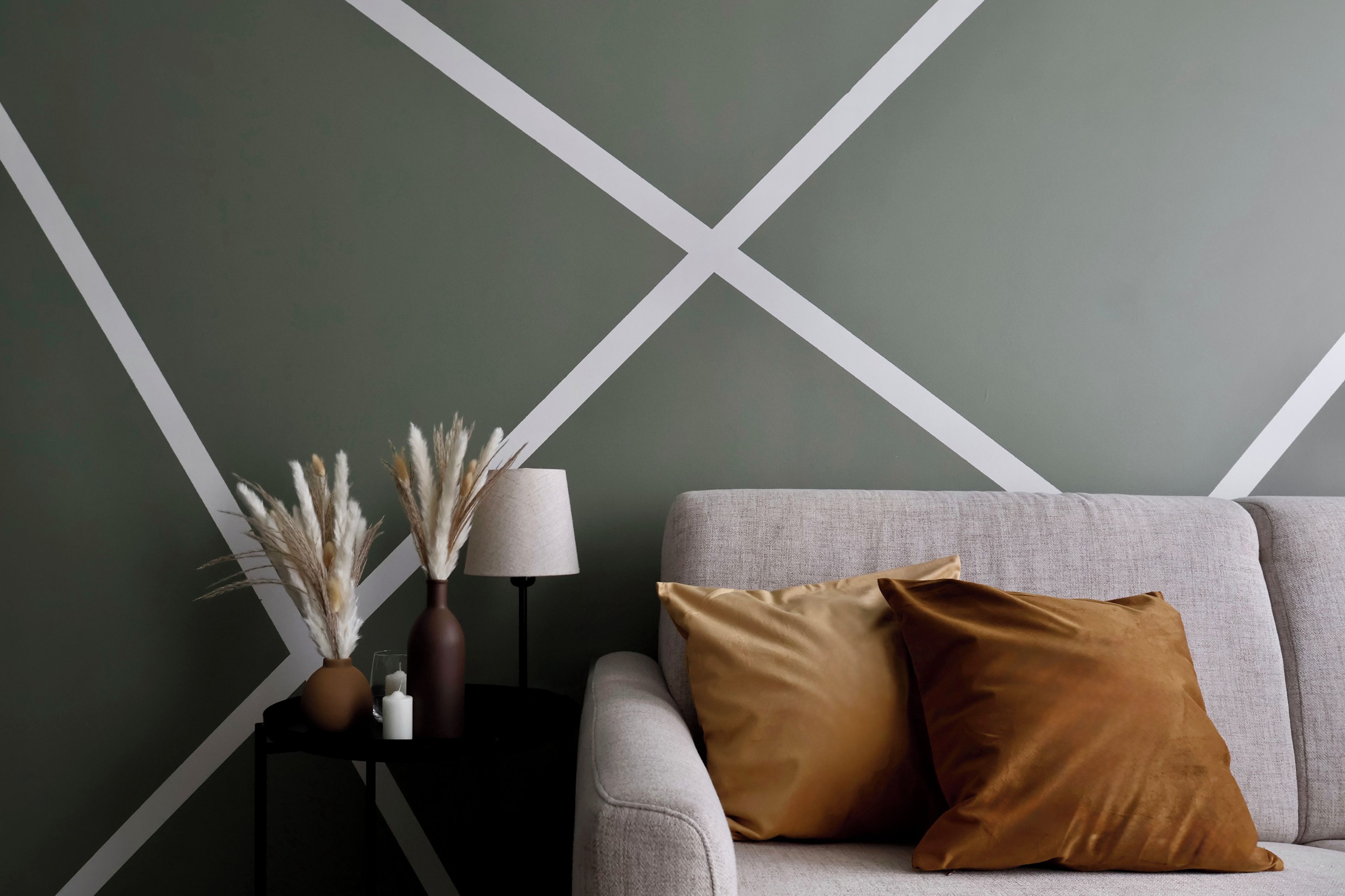 A room with a sofa, a side table, and a wall with a geometric pattern.