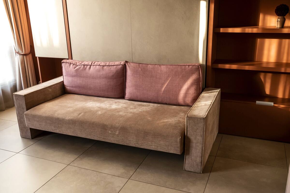 Ein modernes, minimalistisches Wohnzimmer mit einem beigefarbenen Sofa, einem Holztisch und einer eingebauten Regaleinheit.