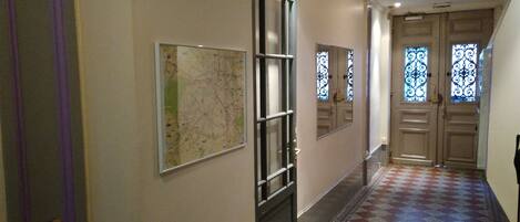 Un pasillo con un mapa en la pared, una puerta con espejo y un piso estampado.