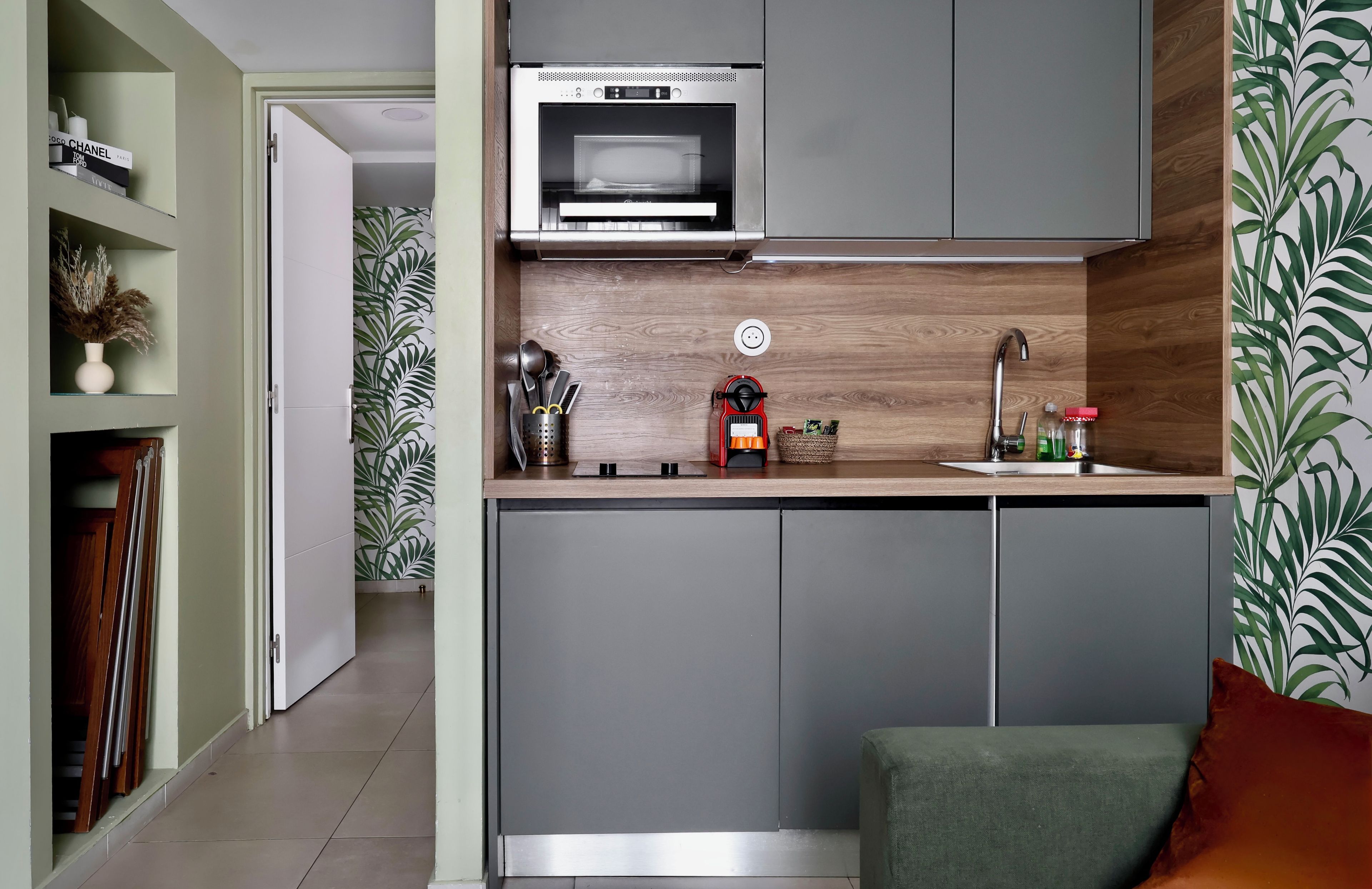 Een moderne keuken met een ingebouwde magnetron, een spoelbak en een houten achterwand.
