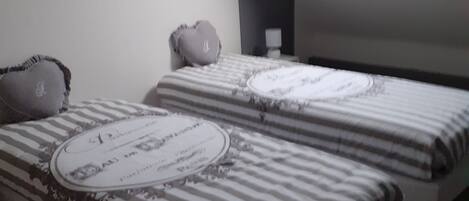 A bedroom with two beds, a skylight, a framed picture, and a bedside table with a lamp.