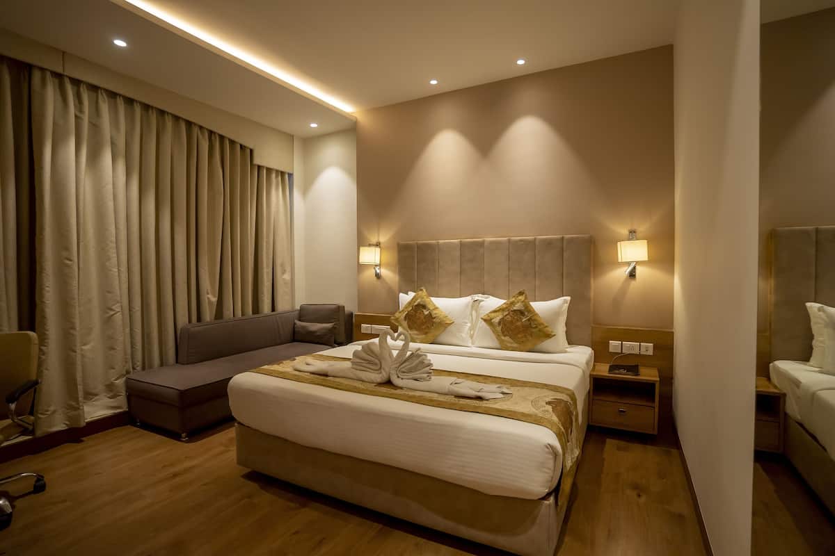 Una habitación de hotel con una cama grande, dos mesitas de noche, un sofá, una silla y una cortina.