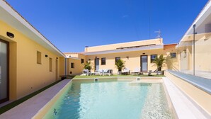 Une piscine avec des chaises longues et un bâtiment en arrière-plan.