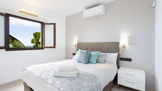 Une chambre moderne avec un grand lit, des lampes de chevet, une table de nuit et un appareil de climatisation.