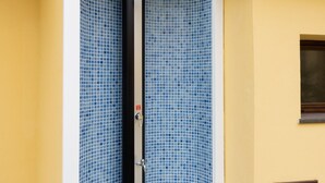 Un coin d'un bâtiment avec un espace de douche carrelé, une petite fenêtre et une porte.