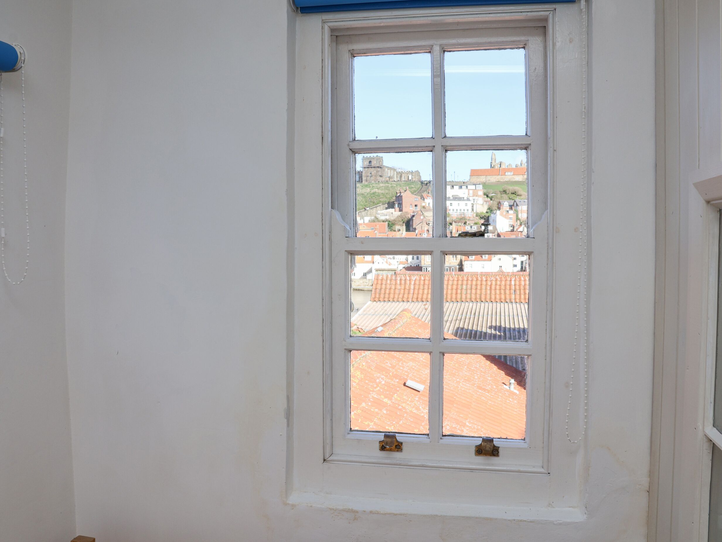 A window with a view of buildings and a hill.