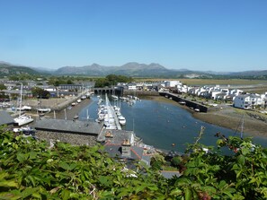 A marina with boats docked, a bridge, and buildings in the background. - Wenallt (Porthmadog)