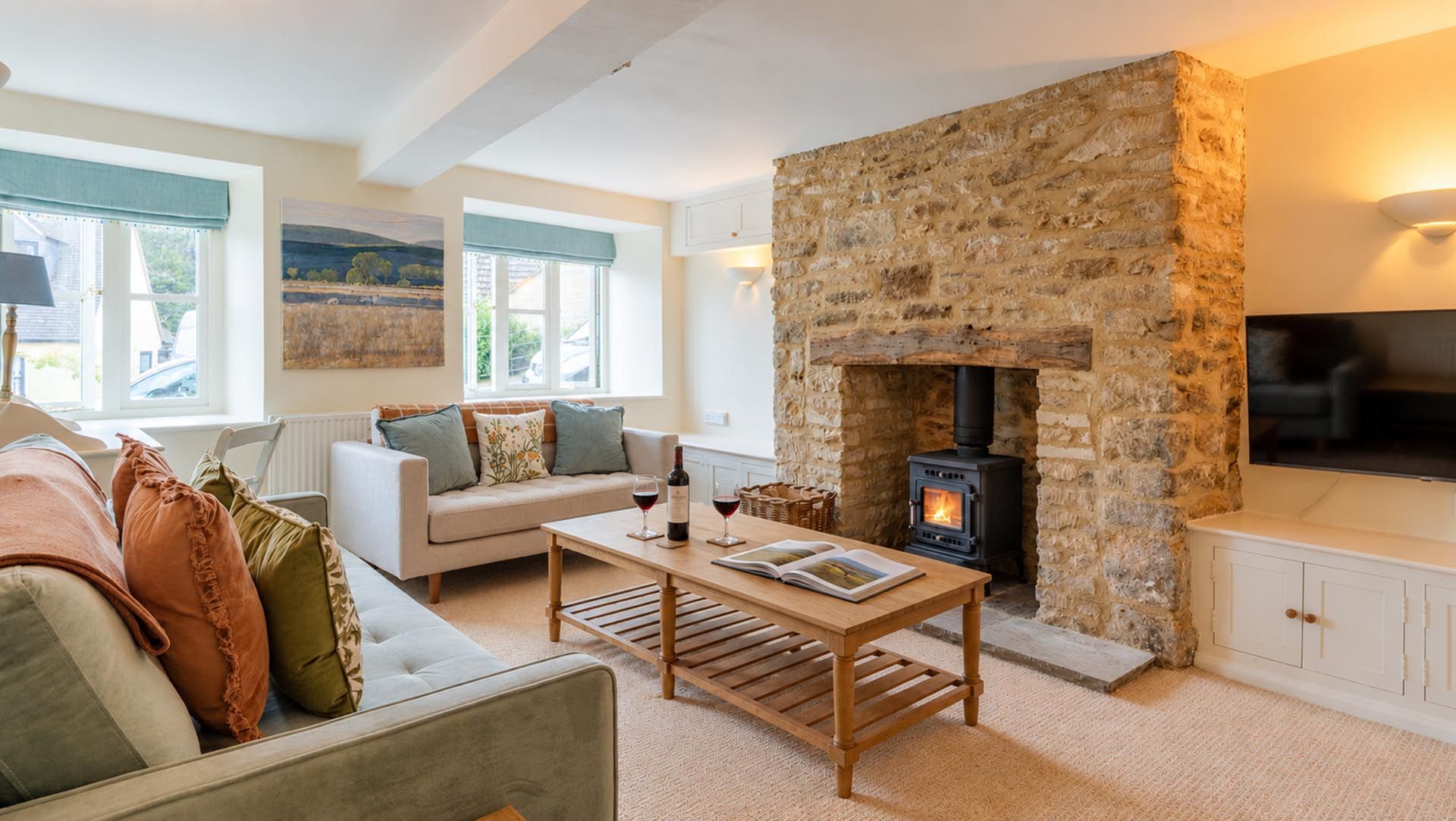 A cozy living room with a stone fireplace, a sofa, a coffee table, and a television.